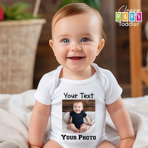 a baby sitting on a bed wearing a white bodysuit