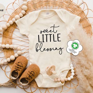 a baby's bodysuit and shoes are on a wicker basket