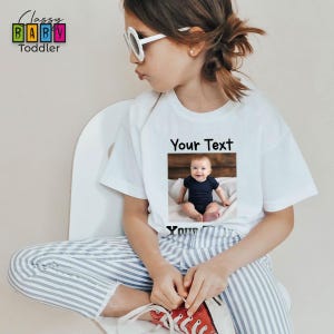 a young girl wearing a t - shirt with a picture of a baby on it