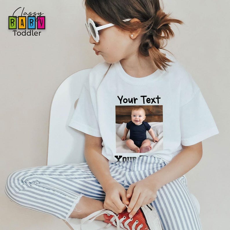 a young girl wearing a t - shirt with a picture of a baby on it