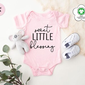a baby bodysuit with a teddy bear and a pair of sneakers