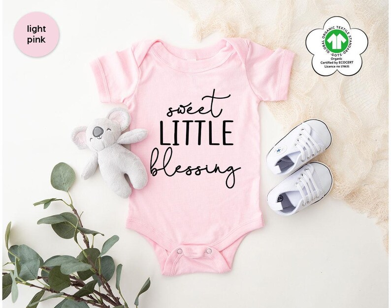 a baby bodysuit with a teddy bear and a pair of sneakers