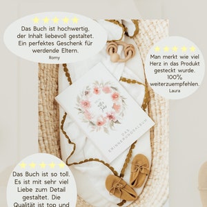 May include: A white baby memory book with a watercolor floral wreath and the text "Mein erstes Jahr" (My First Year) on the cover. The book is lying on a white blanket with a brown and white woven basket in the background. The book is surrounded by positive customer reviews.
