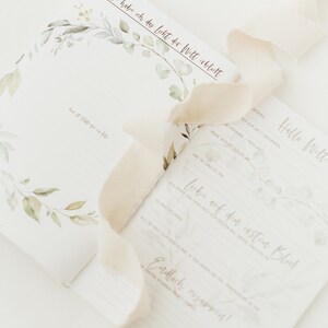 May include: A white card with a floral design and the text "Heute habe ich das Licht der Welt erblickt" (Today I saw the light of the world). The card also has the text "Hello Welt" (Hello World) and "Liebe auf den ersten Blick" (Love at first sight).