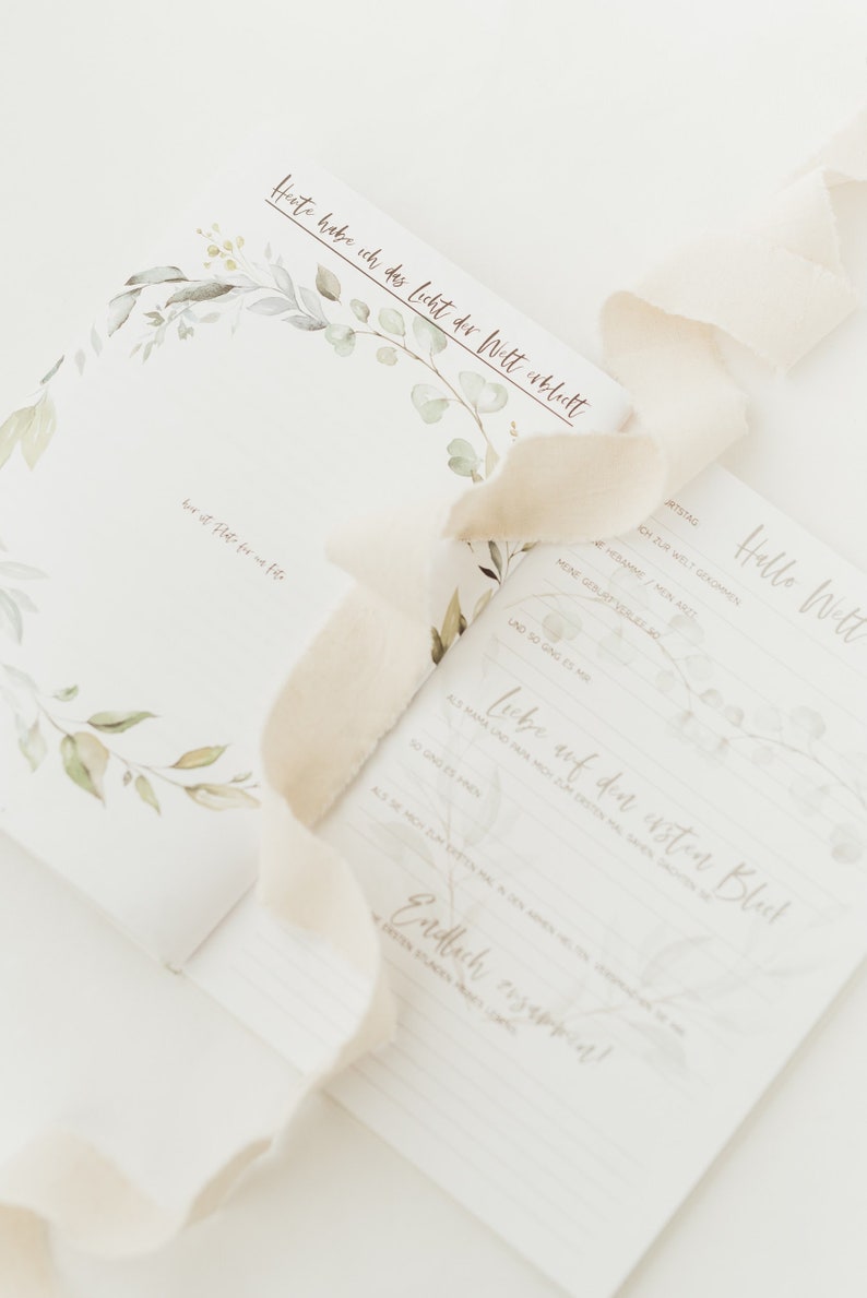May include: A white card with a floral design and the text "Heute habe ich das Licht der Welt erblickt" (Today I saw the light of the world). The card also has the text "Hello Welt" (Hello World) and "Liebe auf den ersten Blick" (Love at first sight).
