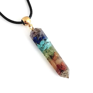 Peut inclure: Un collier avec un pendentif en cristal à sept chakras sur un cordon noir. Le pendentif est un cristal transparent avec sept couches de pierres précieuses de différentes couleurs, représentant les sept chakras.