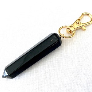 May include: A black obsidian point keychain with a gold metal clasp. The point is smooth and polished.