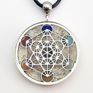 May include: A silver pendant with a clear crystal and a geometric design. The pendant is surrounded by seven colorful stones, including red, orange, yellow, green, blue, indigo, and violet.