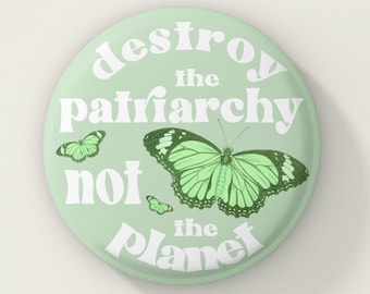 May include: A green button with the text "destroy the patriarchy not the planet" in white. The button features a green butterfly with smaller butterflies in the background.