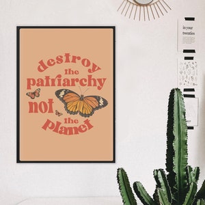 May include: A peach-colored poster with the text "destroy the patriarchy not the planet" in red and orange letters. A large orange butterfly with black markings is centered on the poster. Smaller butterflies are in the corners of the poster.