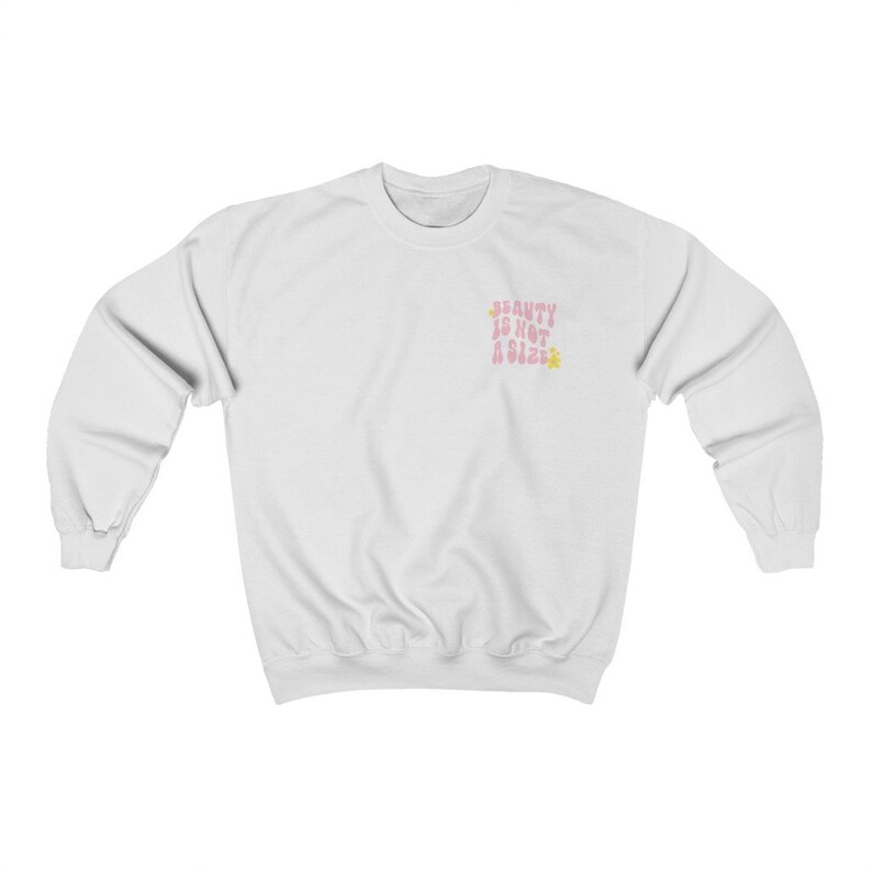 May include: White sweatshirt with a pink graphic that says "Beauty is not a size" with a yellow flower on either side of the text.