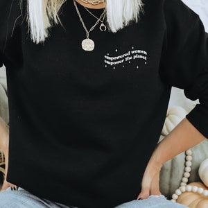 May include: Black sweatshirt with the text "empowered women empower the planet" in white lettering.