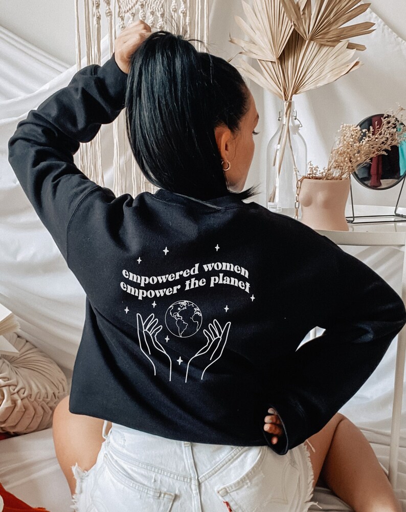 May include: Black sweatshirt with a white graphic print of hands holding a globe and the text "empowered women empower the planet".