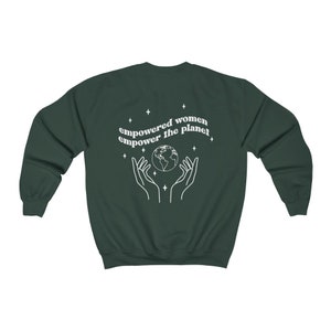 May include: A dark green sweatshirt with the text "empowered women empower the planet" in white. The text is surrounded by small stars and a graphic of two hands holding a globe.