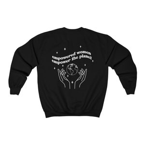 May include: Black sweatshirt with a white graphic design of a globe surrounded by stars and the text "empowered women empower the planet".