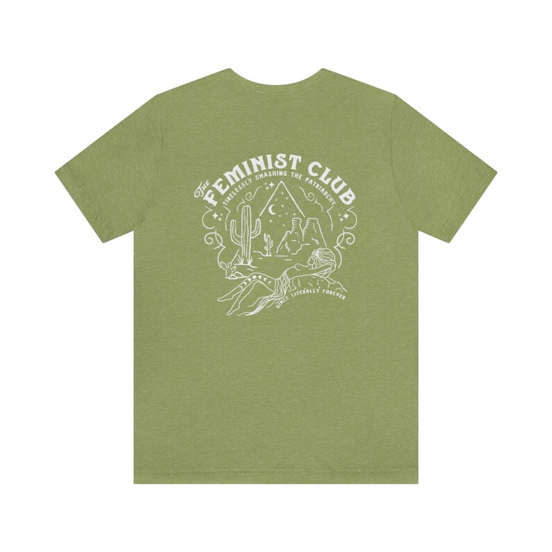 May include: A green t-shirt with a white graphic design on the back. The design features a cactus, mountains, a crescent moon, and stars. The text reads "The Feminist Club: Tirelessly Smashing the Patriarchy. We'll Literally Forever."