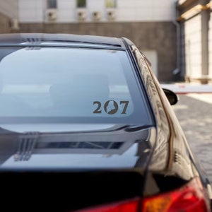 May include: A black car with a sticker on the back window that says "207" with a silhouette of a state.