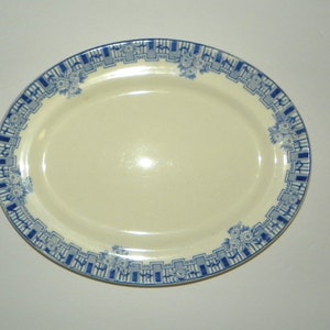 May include: A white oval serving platter with a blue and white geometric pattern around the edge. The pattern features stylized flowers and lines.