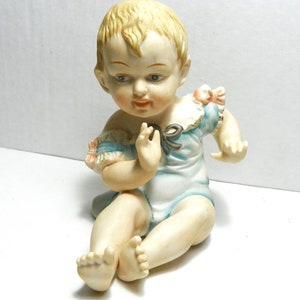 Bisque Piano Baby 23/112 blauwe romper met roze strikken