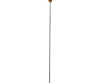May include: A tall, slender, black metal floor lamp with a small, round, gold-colored shade at the top. The lamp is a simple, minimalist design, suitable for various interior styles.