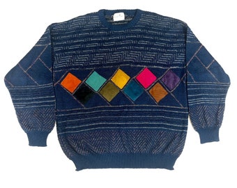 May include: A navy blue sweater with a geometric pattern and colorful diamond-shaped patches. The sweater has a crew neck and long sleeves.