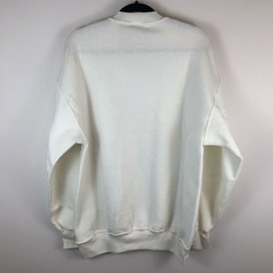 May include: A white sweatshirt with a mock neck and long sleeves.