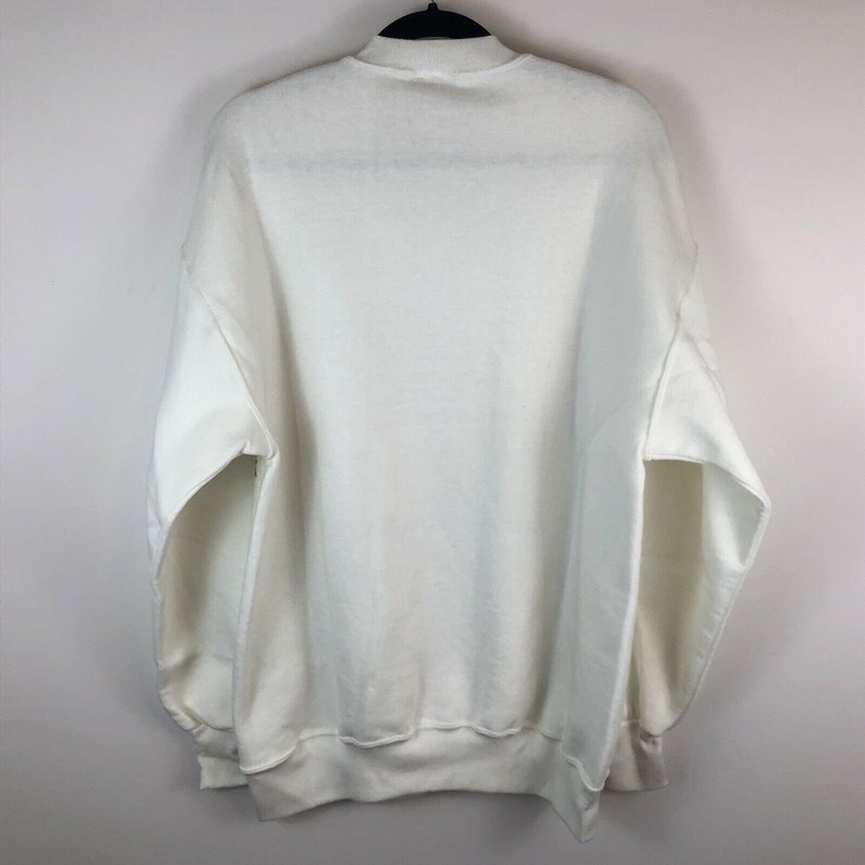 May include: A white sweatshirt with a mock neck and long sleeves.