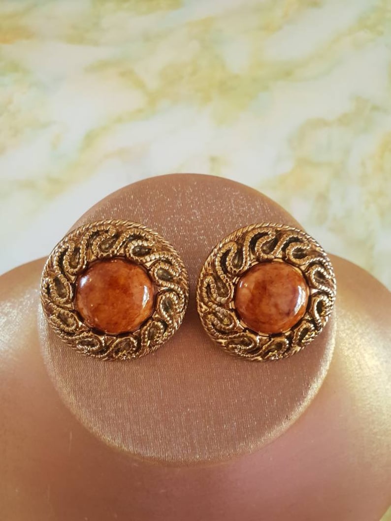 Earings 1980/'s clip on Ornate textured goldtone surrounding a caramel colored acrylic centre.