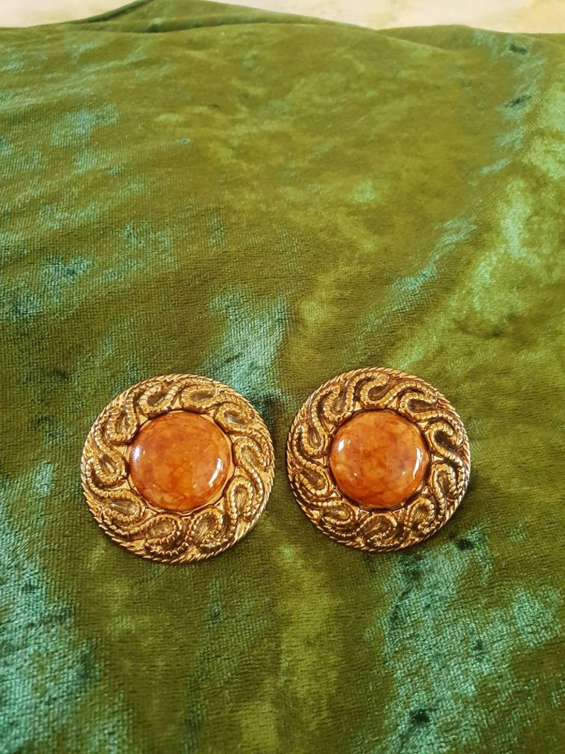 Earings 1980/'s clip on Ornate textured goldtone surrounding a caramel colored acrylic centre.