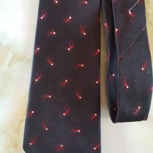 Necktie 1960&#39;s. Ensign Luxura, washable polyester fibre. Dark brown with reddish/white paisley design.