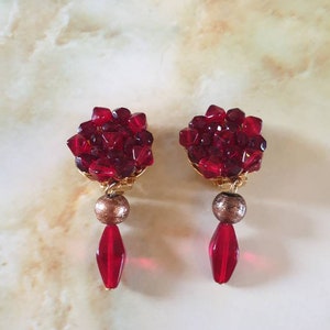 Earings 1980s clip on. Light and dark red faceted glass beads, in a cluster design atop a gold bead and long red bead in a drop design.
