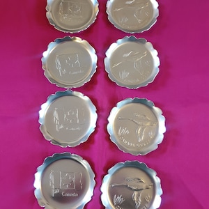 Drink coasters, set of 8. Silver metal with scalloped edges. Raised design of Canadian flag and flying Goose. Millbrook, made in Canada.