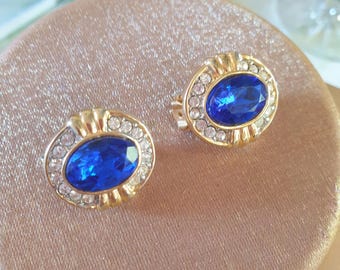 Pendientes de clip de los años 80. De color dorado, con forma ovalada, adornados con diamantes que enmarcan una joya azul facetada en el centro.