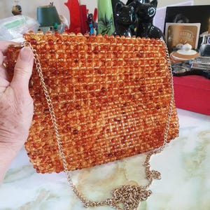 Handtasche mit Schultergurt 1990er Jahre. Braun/gold Acryl Perlen, mit langem goldfarbenem Schlaufenband. Kann auch eine Clutch sein.