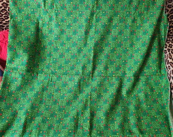 May include: Green fabric with a repeating pattern of small red and yellow flowers and leaves.