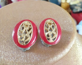 May include: A pair of red and gold oval-shaped clip-on earrings with a delicate filigree design.