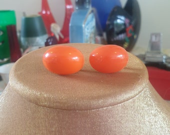 Boucles d'oreilles des années 60 à clip. Acrylique orange en forme d'oeuf en relief.