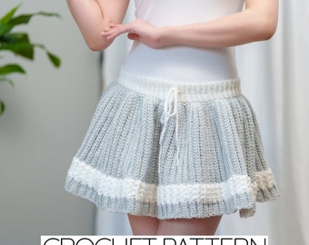 May include: A crochet skirt pattern with a gray and white color scheme. The skirt has a white drawstring and a white crocheted trim around the bottom.
