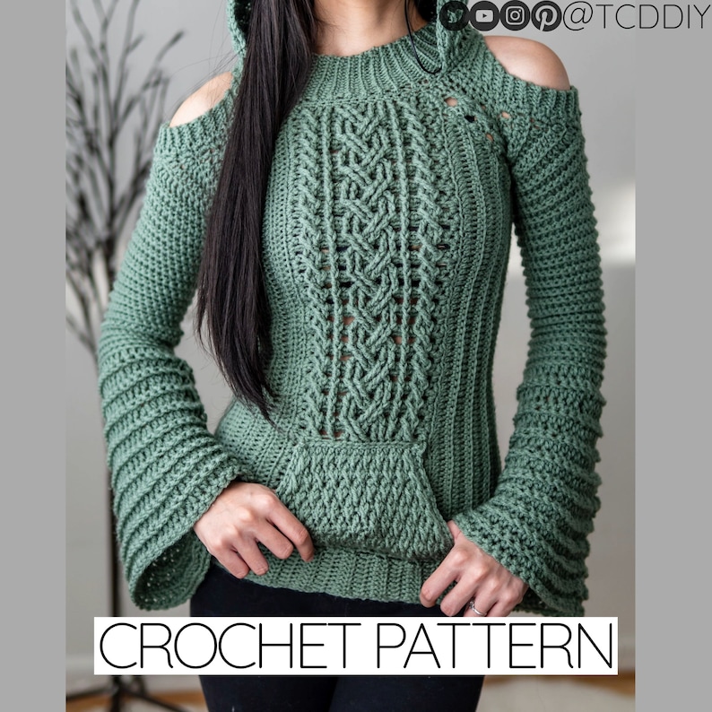 TCDDIY crochet pattern of a cold shoulder bell sleeve hoodie featuring intricate cable stitch detail on the body with alpine stitch hoodie pockets made in light sage yarn.