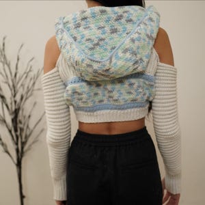 TCDDIY crochet pattern for a cold shoulder cropped hoodie with herringbone hood and thumbholes, crafted using Baby Bernat Sport yarn in White, Cool Blue, and Baby Blue, back view.