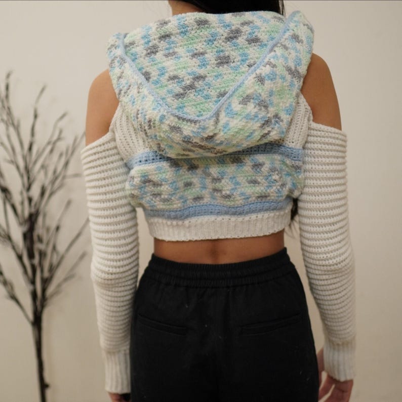 TCDDIY crochet pattern for a cold shoulder cropped hoodie with herringbone hood and thumbholes, crafted using Baby Bernat Sport yarn in White, Cool Blue, and Baby Blue, back view.