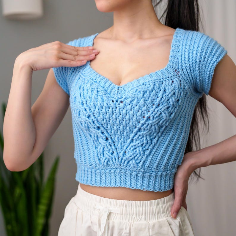 TCDDIY crochet pattern for a sweetheart cable stitch cropped T-shirt top with alpine stitch and ribbed detailing, crafted using Caron One Pound yarn in Pastel Blue.