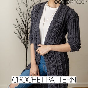 Könnte beinhalten: Ein anthrazitfarbener Häkelcardigan mit einem Zopfmuster. Der Cardigan hat einen V-Ausschnitt und lange Ärmel. Das Model trägt den Cardigan zu einem weißen T-Shirt und einer blauen Jeans. CROCHET PATTERN steht in weißer Schrift am unteren Rand des Bildes.