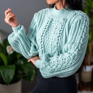 TCDDIY crochet pattern for a cropped cable stitch sweater with a mock neck and alpine stitch detailing, crafted using Caron One Pound yarn in Pale Green.