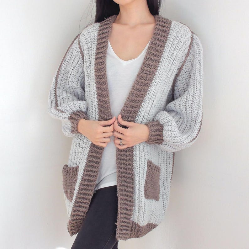 TCDDIY crochet pattern for an Oversized Reversible Cardigan featuring a ribbed two-toned design, pockets, crafted using Lion Brand Pound of Love yarn in Elephant Grey and Taupe.