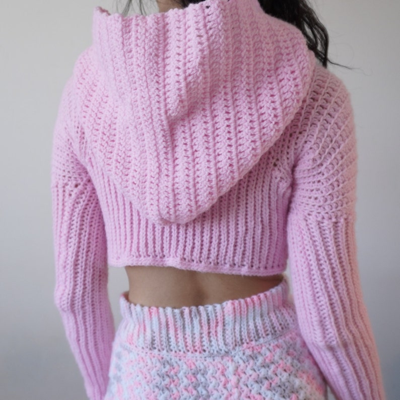 TCDDIY crochet pattern for a Long Sleeve Cropped Hoodie with thumbhole cuffs, ribbed sleeves, crafted using Lion Brand Pound of Love yarn in Pastel Pink, back view hood down.