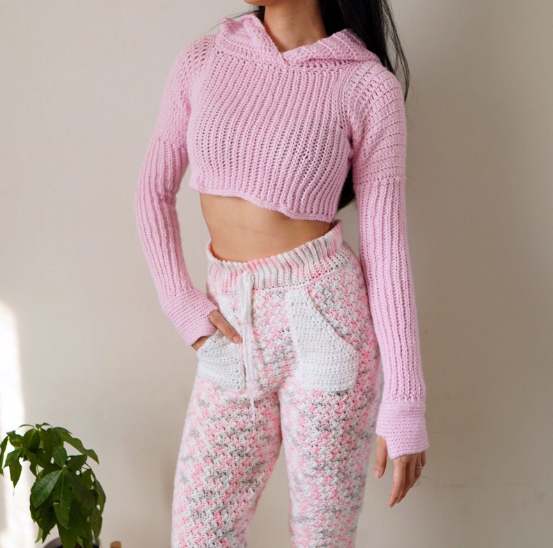 TCDDIY crochet pattern for a Long Sleeve Cropped Hoodie with thumbhole cuffs, ribbed sleeves, and customizable sizing, crafted using Lion Brand Pound of Love yarn in Pastel Pink.