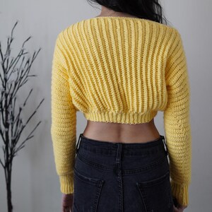 TCDDIY crochet pattern for a cropped off-the-shoulder V-neck sweater with versatile styling options, made with Lion Brand Pound of Love yarn in Honey Bee, back view.
