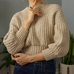 TCDDIY crochet pattern for a modern wide-collar Trinity stitch 3/4 sleeve sweater with a customizable fit, crafted using Baby Bernat Sport yarn in Baby Taupe.