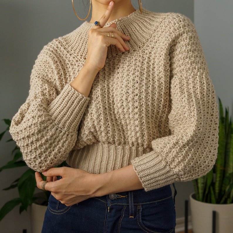 TCDDIY crochet pattern for a modern wide-collar Trinity stitch 3/4 sleeve sweater with a customizable fit, crafted using Baby Bernat Sport yarn in Baby Taupe.